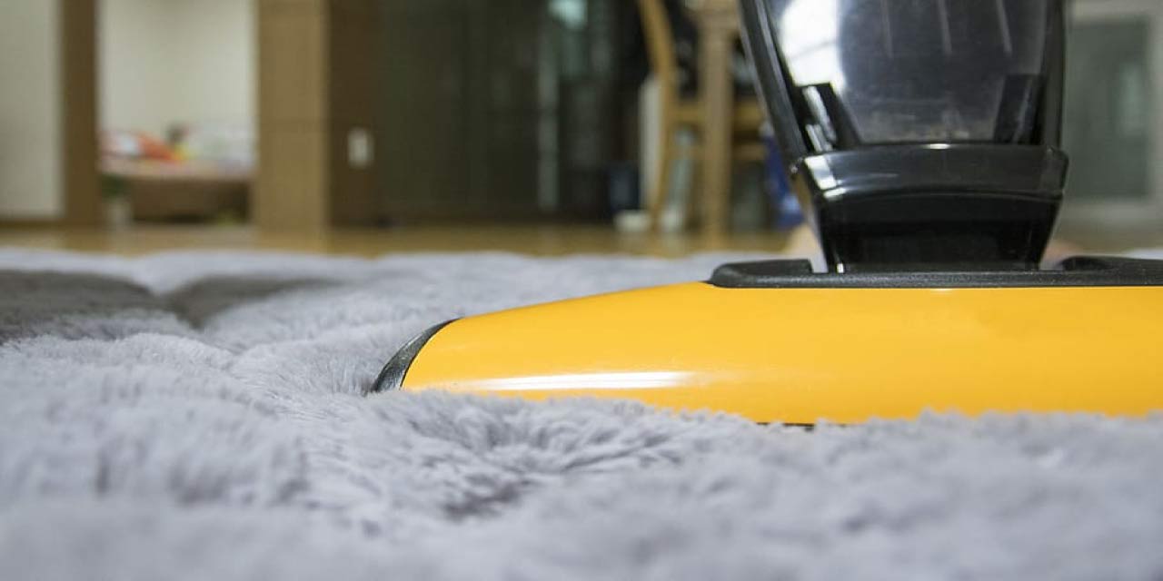 yellow and black upright vacuum on gray fleece rug inside room